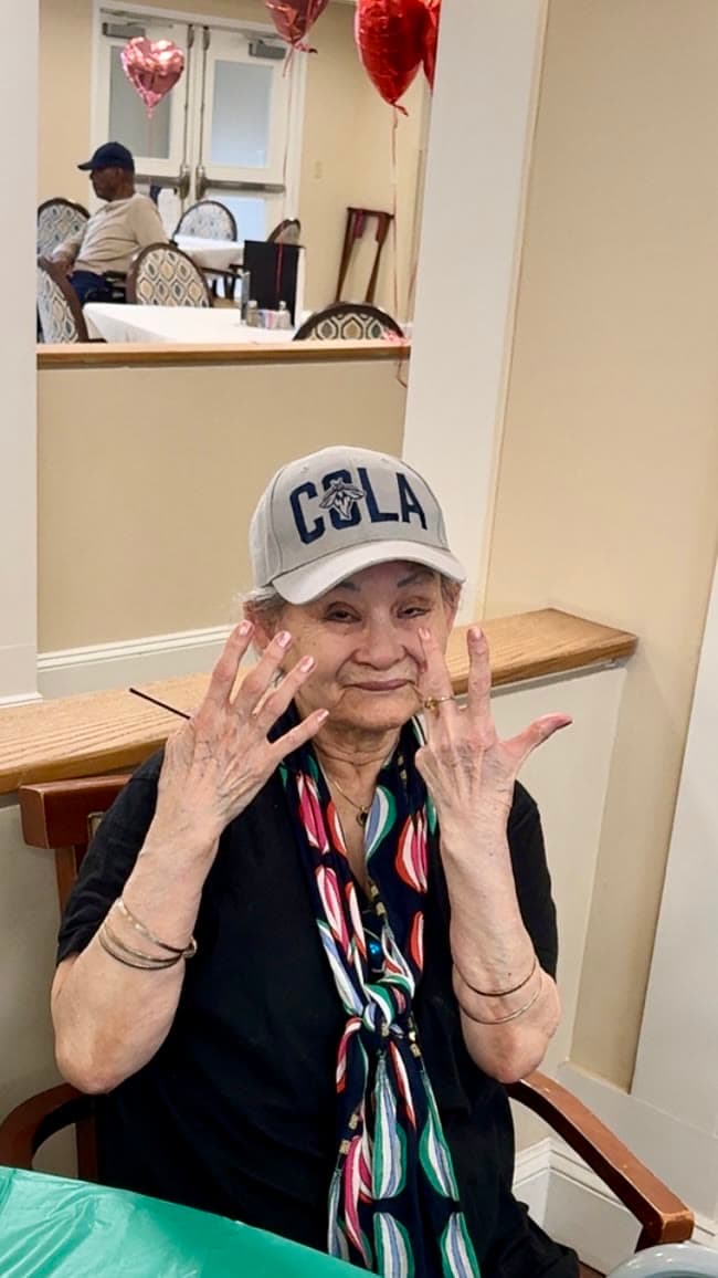 A senior resident smiling and showing off her freshly polished nails